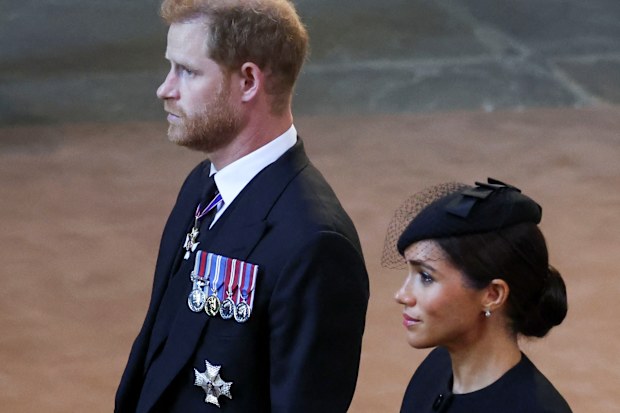 LONDON, ENGLAND - SEPTEMBER 14: Prince Harry, Duke of Sussex and Meghan, Duchess of Sussex walk as procession with the coffin of Britain's Queen Elizabeth arrives at Westminster Hall from Buckingham Palace for her lying in state, on September 14, 2022 in London, United Kingdom. Queen Elizabeth II's coffin is taken in procession on a Gun Carriage of The King's Troop Royal Horse Artillery from Buckingham Palace to Westminster Hall where she will lay in state until the early morning of her funeral.