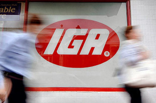 Pedestrians walk past IGA supermarket window in Sydney (Getty)