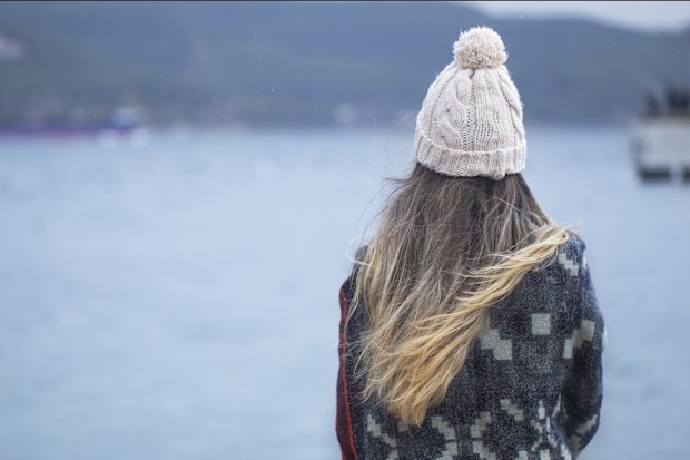 Woman sitting alone on the pier in cold weather
