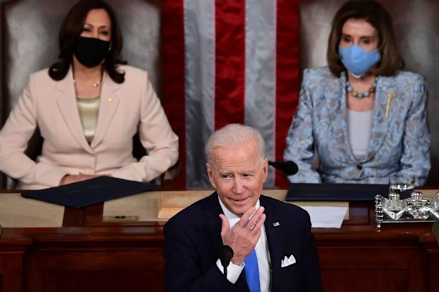 Joe Biden speaks to Congress, flanked by Kamala Harris and Nancy Pelosi.