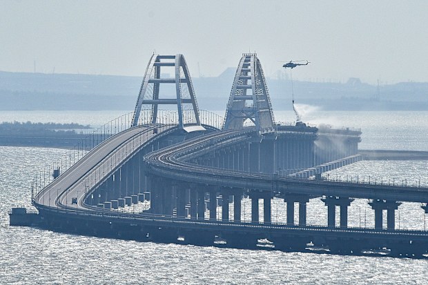 A helicopter drops water to stop fire on Crimean Bridge connecting Russian mainland and Crimean peninsula over the Kerch Strait, in Kerch, Saturday, Oct. 8, 2022. 
