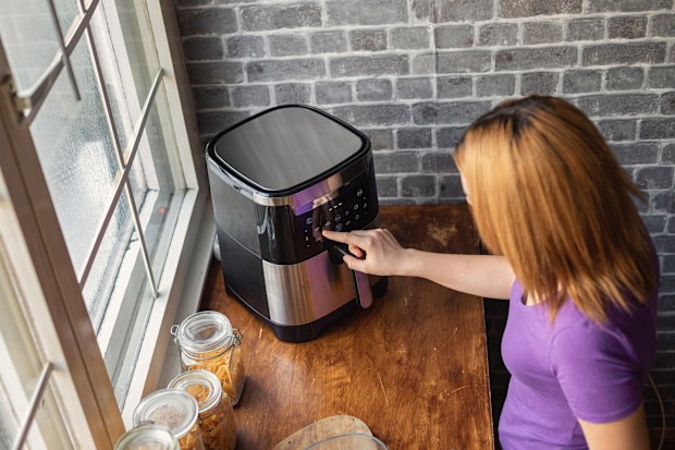 woman using an air fryer in the kitchen to prepare french fries