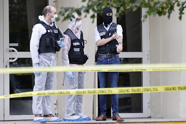 French investigating officers stand in front of the Gambetta high school in Arras, northeastern France, after a man armed with a knife killed a teacher and wounded another teacher and a security guard, an attack being investigated as potential terrorism, Friday Oct. 13, 2023.
