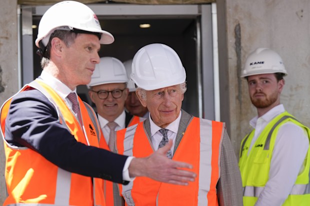 Britain's King Charles III, center, is assisted by Albanese and New South Wales Premier Chris Minns, left, while Australia's Prime Minister Anthony Albanese walks behind as he visits the Homes NSW Cowper Street development in Sydney, Australia, Tuesday, Oct. 22, 2024. 