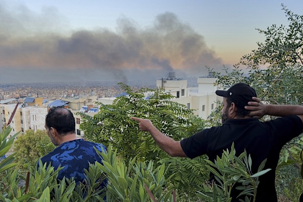 Lebanese citizens watch smoke rise from Israeli airstrikes in the southern suburbs of Beirut, Lebanon, Saturday, Sept. 28, 2024. 