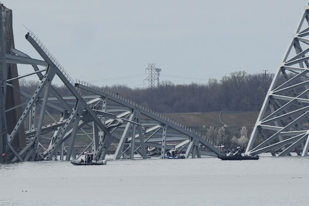 Boats move near a container ship as it rests against wreckage of the Francis Scott Key Bridge on Tuesday, March 26, 2024, as seen from Dundalk, Md. 