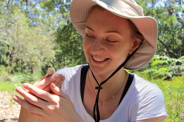 Dr Emily Roycroft in the field with a small reptile.