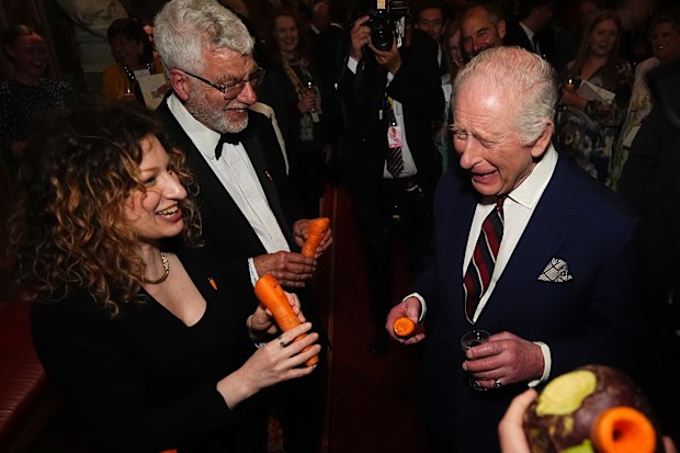 WINDSOR, ENGLAND - APRIL 3: King Charles III plays a carrot with the London Vegetable Orchestra during a reception to recognise those involved in community music across the UK, at Windsor Castle on April 3, 2025 in Windsor, England. The 350 guests include leaders of community music groups and music-related projects, many of whom are volunteers. (Photo by Aaron Chown - WPA Pool/Getty Images)