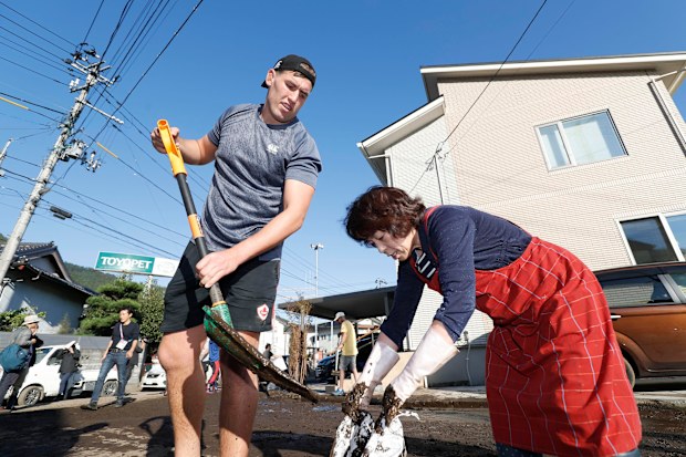 Canadian rugby player Josh Larsen, left, helps a resident to clean a road in Kamaishi, Iwate prefecture, Japan, following the cancellation of their Rugby World Cup Pool B match against Namibia due to Typhoon Hagibis. 