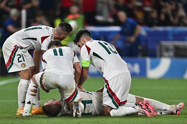 Barnabas Varga of Hungary lies on the ground and is assisted by teammates after a collision with goalkeeper Angus Gunn of Scotland.