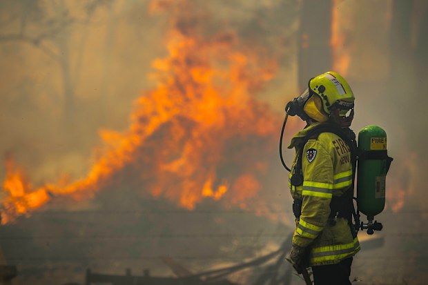 Firefighter Adam Brown from FRNSW protects properties along Glenthorne Rd in South Taree from an out of control bushfire, 10th November 2019. 