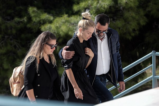 Red-eyed widow Viktoria has to be helped up the steps to the funeral service of her murdered husband.