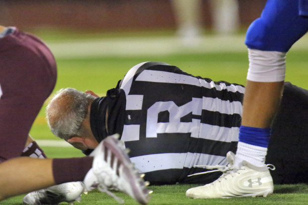 Football referee Fred Gracia lays on the ground right after being charged by Edinburg High's Emmanuel Duron.