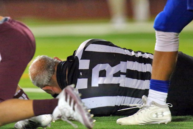Football referee Fred Gracia lays on the ground right after being charged by Edinburg High's Emmanuel Duron.