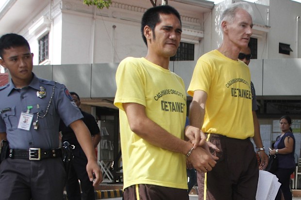 Peter Gerald Scully of Australia, right, walks in handcuffs with an unidentified detainee as they arrive at Cagayan de Oro city hall in southern Philippines on Tuesday, June 16, 2015. (AAP)