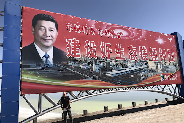 Mike Smith pictured beneath a huge poster of Xi Jinping.