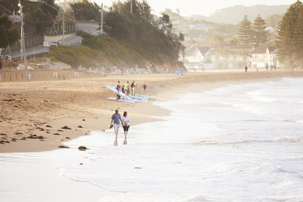 Couple enjoying a walk across Terrigal Beach on the Central Coast.