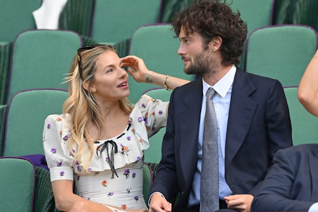 Sienna Miller and Oli Green react to the action court-side on day nine of the Wimbledon Tennis Championships at the All England Lawn Tennis and Croquet Club on July 08, 2025 in London, England. 