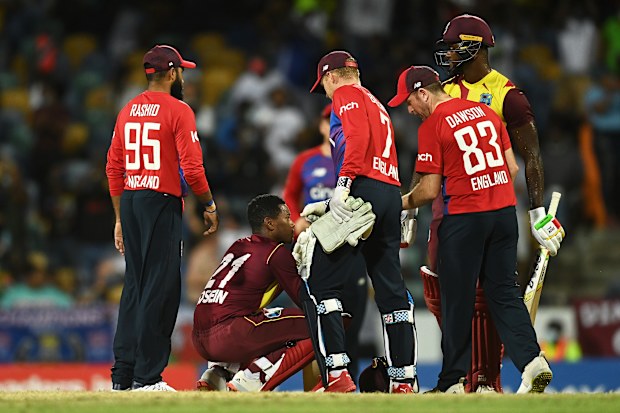 Akeal Hosein of West Indies cuts a dejected figure as England players console him.