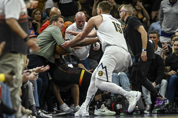 PHOENIX, AZ - MAY 7: Nikola Jokic (15) of the Denver Nuggets rushes to retrieve the game ball as Phoenix Suns owner Mat Ishbia inserts himself into the action by clutching the ball as he helps Josh Okogie (2) to his feet after Okogie flew into the stands during the second quarter at Footprint Center in Phoenix on Sunday, May 7, 2023. (Photo by AAron Ontiveroz/The Denver Post)