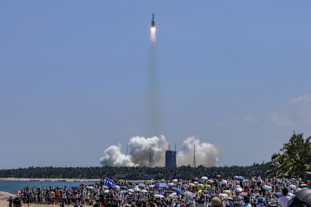 FILE - In this photo released by Xinhua News Agency, people gather at the beach as they watch the Long March 5B Y3 carrier rocket, carrying Wentian lab module, lift off from the Wenchang Space Launch Center in Wenchang in southern China's Hainan Province on July 24, 2022. 
