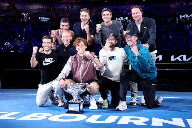 Jannik Sinner of Italy and his team, including Darren Cahill (bottom right) pose with the Norman Brookes Challenge Cup after his men's singles final match against Daniil Medvedev during the 2024 Australian Open.