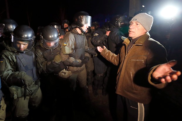 Protesters, who planned to stop buses carrying passengers evacuated from the Chinese city of Wuhan, speak to Ukrainian riot police.