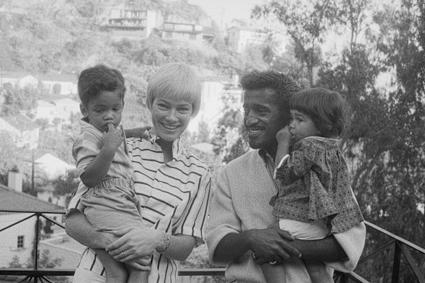 Sammy Davis, Jr., and his wife, actress May Britt, pose with their adopted son Mark Sidney Davis (left). Sammy holds their 16-month-old daughter, Tracey. 
