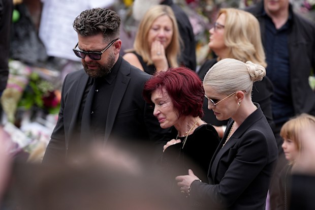 BIRMINGHAM, ENGLAND - JULY 30: Jack Osbourne, Sharon Osbourne, Kelly Osbourne and family members stop to view tributes to the late Ozzy Osbourne from fans at Black Sabbath Bench and Bridge as his funeral cortege travels through his home city of Birmingham on July 30, 2025 in Birmingham, England. The Black Sabbath frontman passed away on July 22nd at the age of 76. His death occurred just a little over two weeks after his final live performance at the 'Back to the Beginning' concert in his hometo