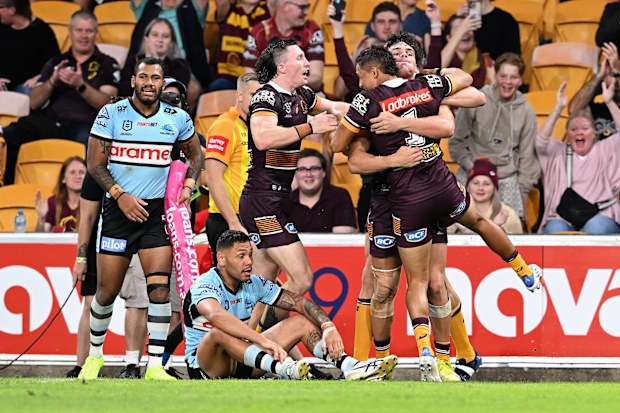 Broncos players celebrate a try against the Sharks.