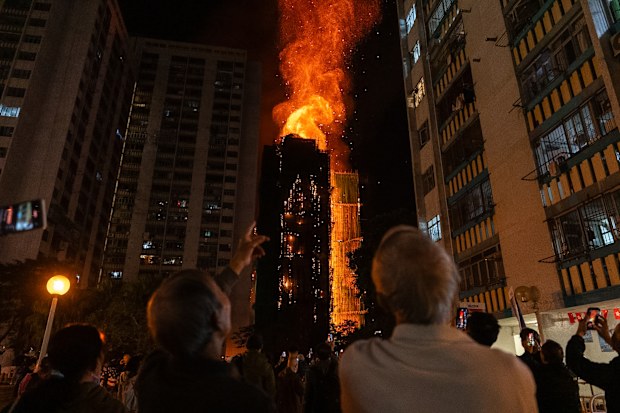 People look at flames engulfing a building after a fire broke out at Wang Fuk Court, a residential estate in the Tai Po district of Hong Kong's New Territories, Wednesday, Nov. 26 2025. (AP Photo/Chan Long Hei)
