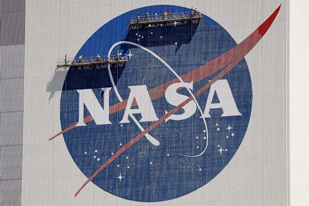 Workers on scaffolding repaint the NASA logo near the top of the Vehicle Assembly Building at the Kennedy Space Center in Cape Canaveral, Fla., Wednesday, May 20, 2020. On Thursday, June 9, 2022, NASA announced it is launching a study of UFOs as part of a new push toward high-risk, high-impact science, setting up an independent team to see how much information is publicly available on the matter and how much more is needed. (AP Photo/John Raoux, File)