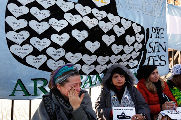 Lucia Zunda Meoqui, sister of Adrian Zunda Meoqui, left, an Argentine Navy officer of the "ARA San Juan" submarine that sank and disappeared on Nov. 15, 2017, cries as she and others chain themselves to the fence of Government House in Buenos Aires, Argentina, Thursday, June 28, 2018. They are demanding that the Government find the ship. (AP Photo Jorge Saenz)