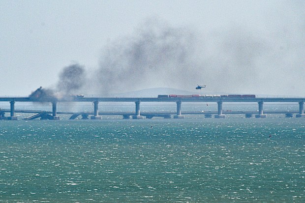 A helicopter flies to drop water to stop fire on Crimean Bridge connecting Russian mainland and Crimean peninsula over the Kerch Strait, in Kerch, Crimea, Saturday, Oct. 8, 2022. 
