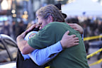 Edward Bruski, right, hugs New Orleans police officer Zachary Stevenson at the scene where a vehicle drove into a crowd on New Orleans' Canal and Bourbon Street, Wednesday Jan. 1, 2025. (AP Photo/Gerald Herbert)