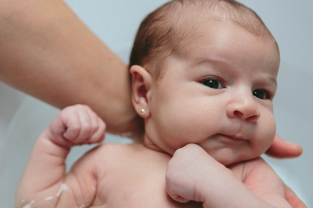 Closeup of newborn girl in the bathtub held by her mother