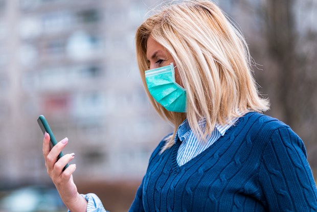 Woman wearing a face mask and using her phone.
