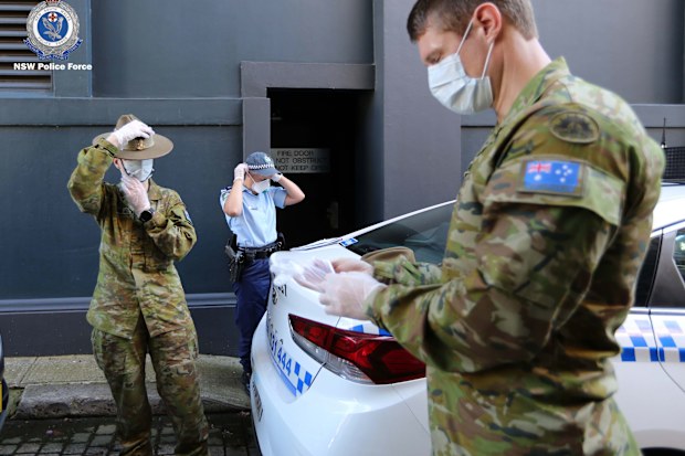 ADF and NSW Police officers put on protective clothing before conducting coronavirus isolation checks.