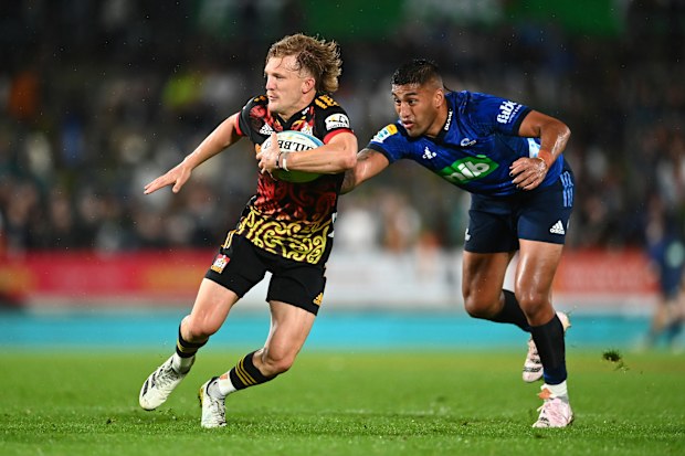Damian McKenzie of the Chiefs gets past Rieko Ioane of the Blues.