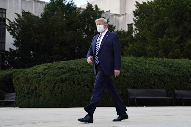 A masked Donald Trump walks out of the hospital this morning.