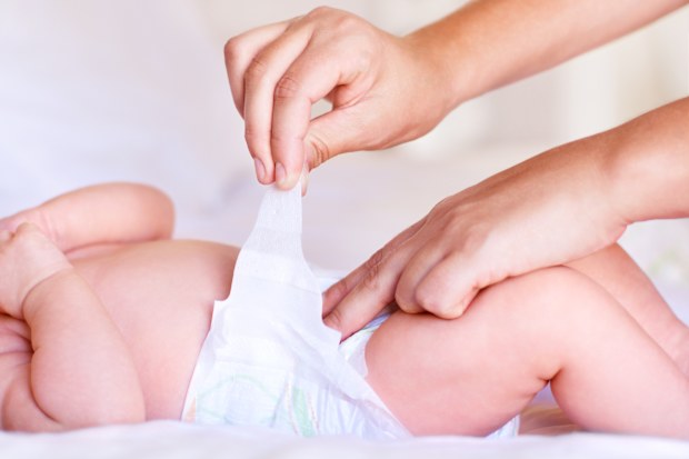 Cute baby boy relaxing while receiving a diaper change