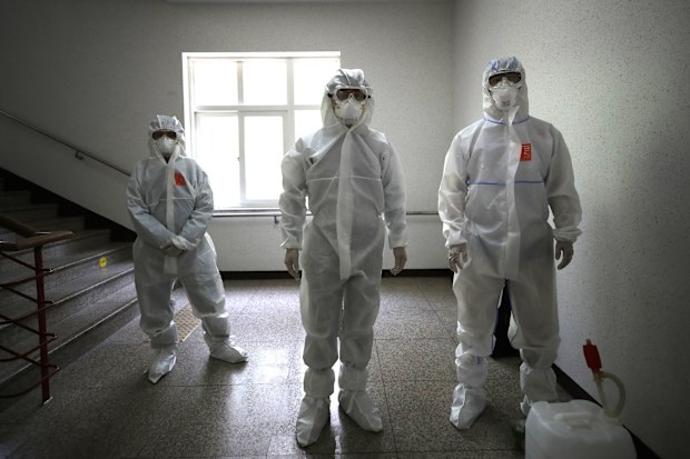 Health officials wearing protective gear prepare to spray disinfectant to help reduce the spread the new coronavirus ahead of school reopening in a cafeteria at a high school in Seoul, South Korea