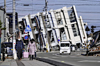 People make their way near a collapsed building due to an earthquake in Wajima, Ishikawa prefecture, Japan Tuesday, Jan. 2, 2024. A series of powerful earthquakes hit western Japan, damaging buildings, vehicles and boats, with officials warning people in some areas on Tuesday to stay away from their homes because of a risk of more strong quakes. (Kyodo News via AP)