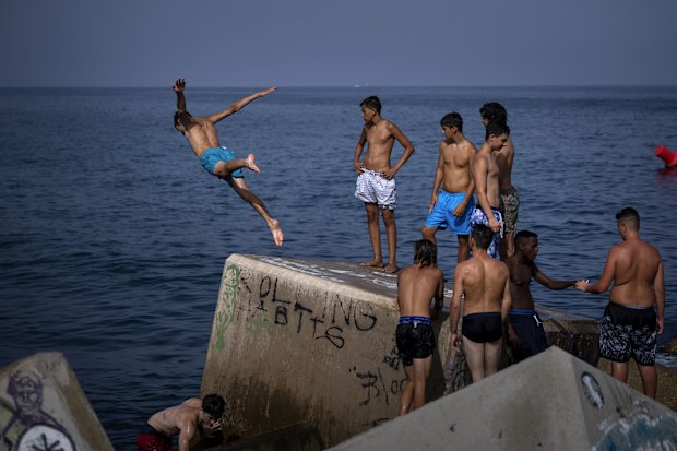 A man jumps into the sea on a breakwater in Barcelona, Spain.