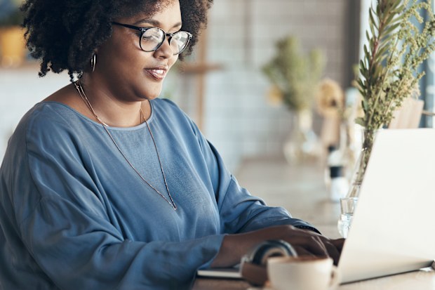 A businesswoman sitting and working on her laptop in a coffee shop during the day