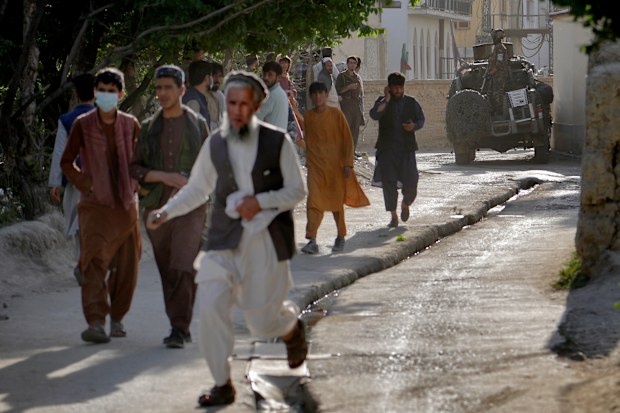 People leave the site of an explosion as a Taliban fighter stands guard in Kabul, Afghanistan, Friday, April 29, 2022. A powerful explosion ripped through a mosque in the Afghan capital of Kabul on Friday, killing at least 10 people and wounding 20, a Taliban spokesman said. (AP Photo/Ebrahim Noroozi)