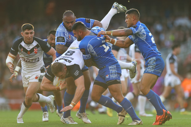 Tom Burgess of England is tackled by Junior Paulo, Royce Hunt and Fa'amanu Brown of Samoa during the Rugby League World Cup Semi-Final match between  England and Samoa at Emirates Stadium on November 12, 2022 in London, England. (Photo by Michael Steele/Getty Images)