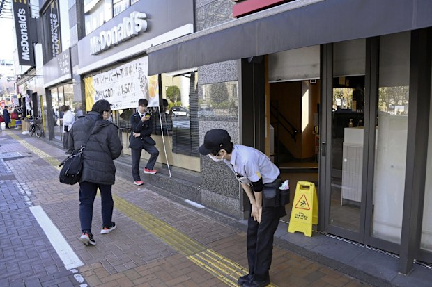A McDonald's employee bows in front of its store amid the company's system outages in Tokyo, Friday, March 15, 2024.  