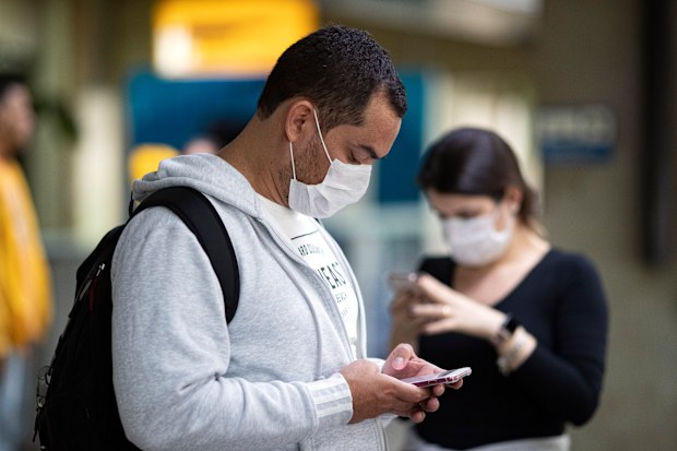 Passengers wearing masks as a precaution against the spread of the new coronavirus COVID-19 use their phones at the Sao Paulo International Airport in Sao Paulo, Brazil, Thursday, Feb. 27, 2020. (AP Photo/Andre Penner)