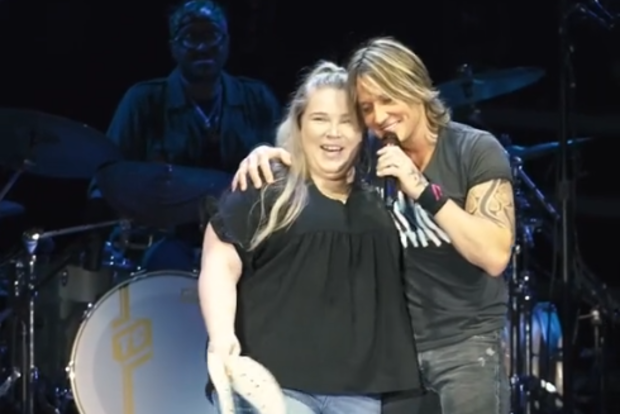 Keith Urban with fan on stage.